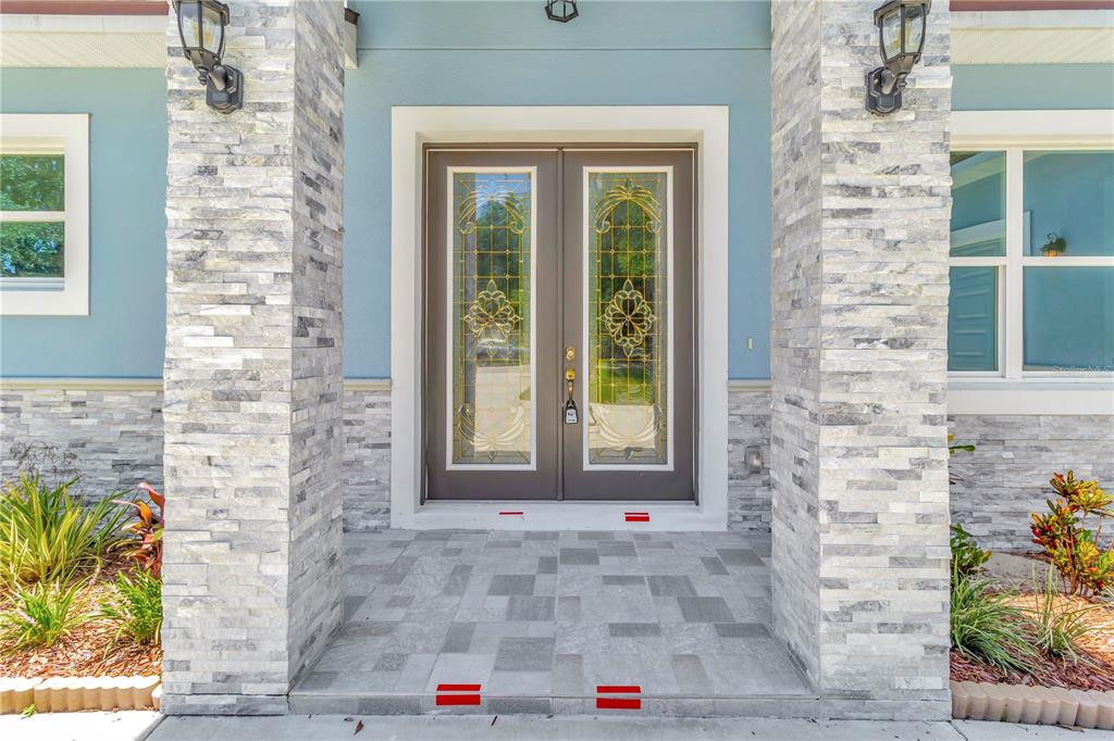 A front entryway features double glass doors flanked by stone pillars and light blue siding — 319 WATER SHORE DRIVE, LEESBURG, FL