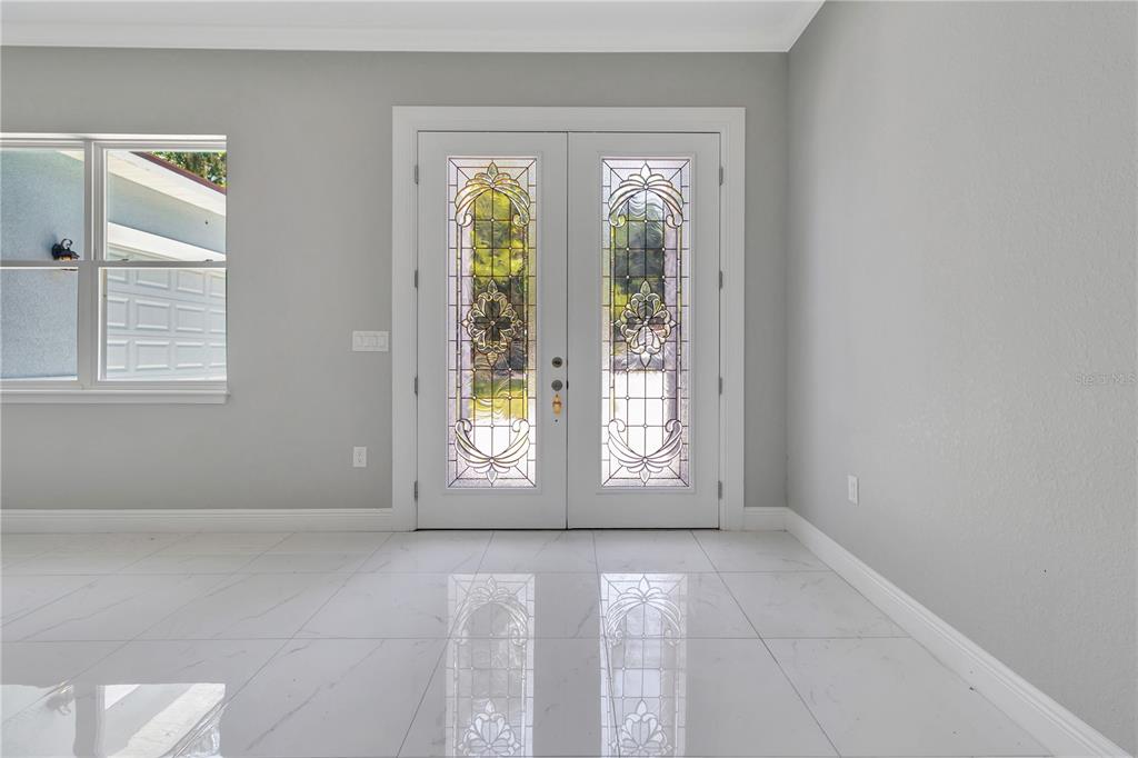 A bright room features white tile floors, gray walls, and double front doors with decorative glass — 319 WATER SHORE DRIVE, LEESBURG, FL