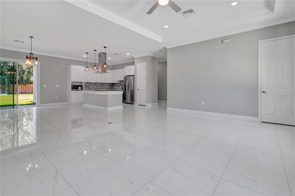 A bright, open-concept kitchen and living area featuring white cabinetry, a kitchen island, and tile flooring — 319 WATER SHORE DRIVE, LEESBURG, FL