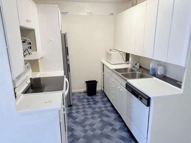 A galley kitchen features white cabinets, a black stove, a dishwasher, and blue patterned flooring — 408 Grantham A # 408, Deerfield Beach FL 33442, DEERFIELD BEACH, FL