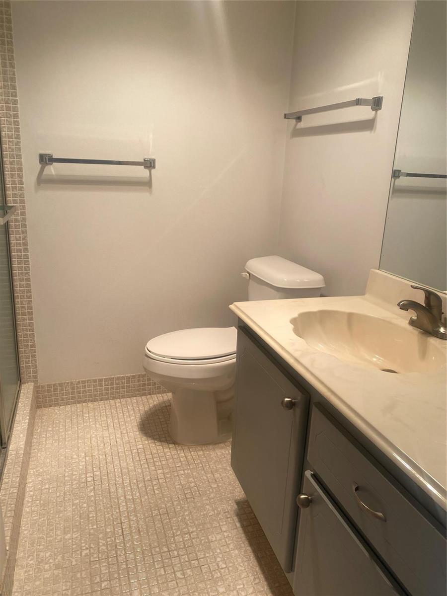 A bathroom features a vanity with a beige sink, a toilet, and tiled flooring — 408 Grantham A # 408, Deerfield Beach FL 33442, DEERFIELD BEACH, FL