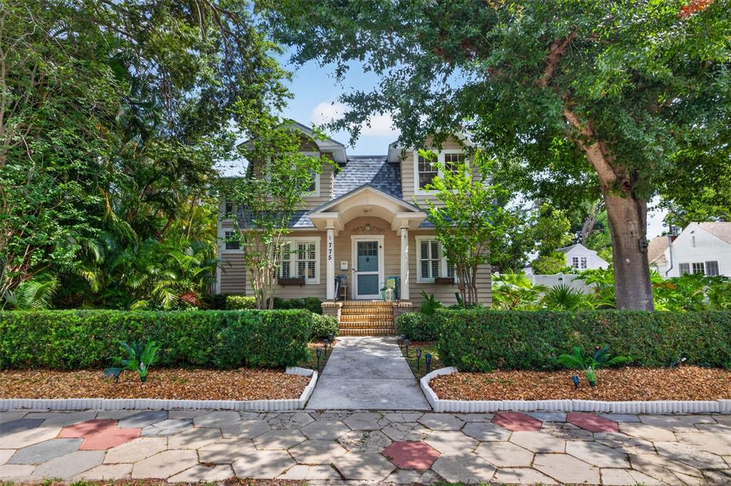 A two-story house with tan siding, a front porch, and a landscaped yard — 775 28TH AVENUE N, ST PETERSBURG, FL