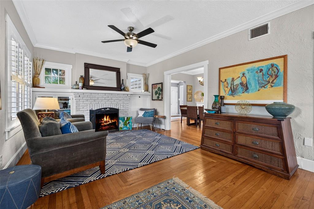 A living room features a white brick fireplace, hardwood floors, and a blue patterned rug — 775 28TH AVENUE N, ST PETERSBURG, FL