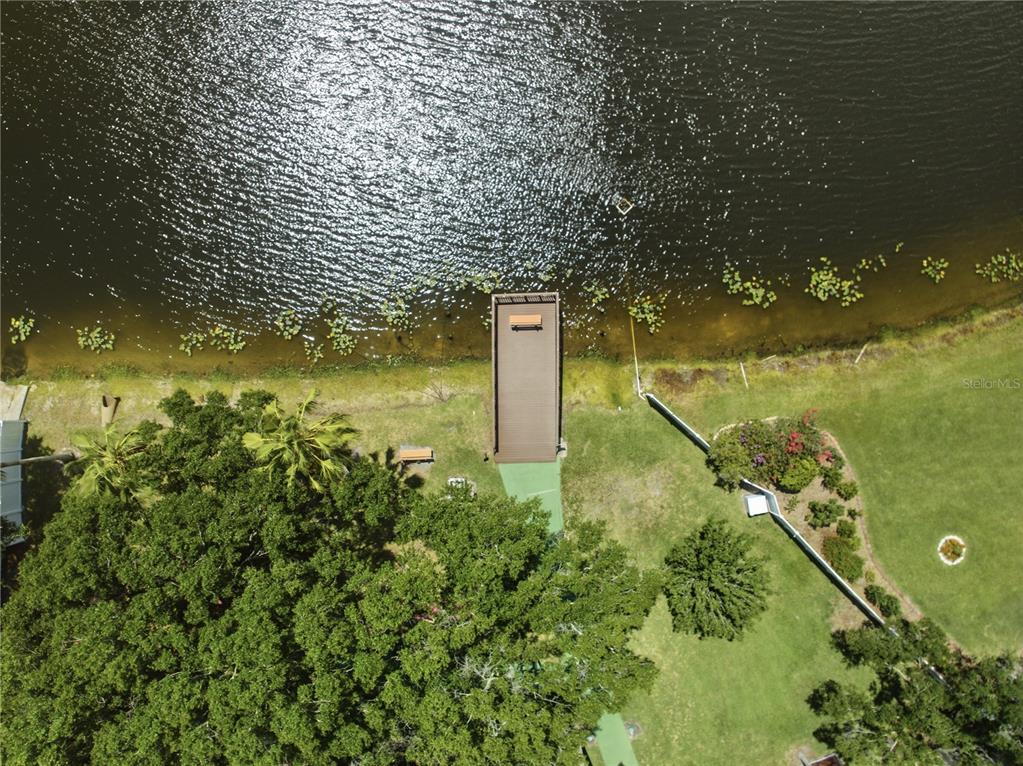 An aerial view shows a wooden dock extending into a lake from a grassy yard — 123 LOBLOLLY COURT UNIT B, OLDSMAR, FL