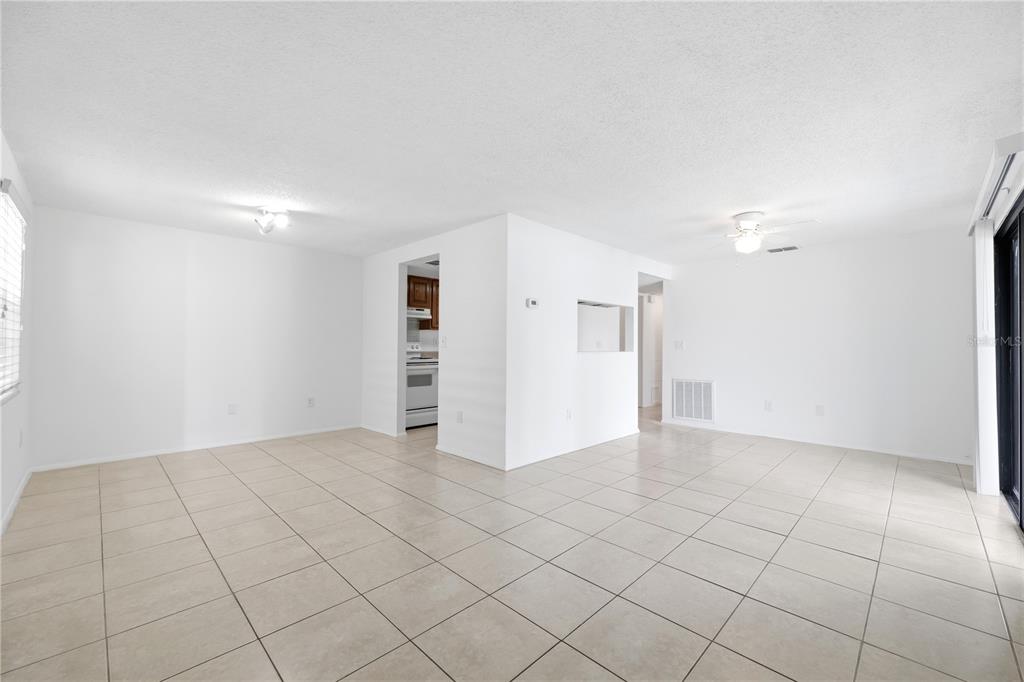 An open-concept living area features white walls, light-colored tile flooring, and a ceiling fan — 123 LOBLOLLY COURT UNIT B, OLDSMAR, FL