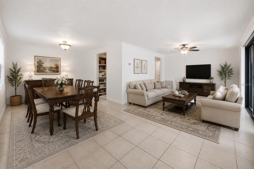 An open-concept living and dining room with tile flooring, neutral furniture, and area rugs — 123 LOBLOLLY COURT UNIT B, OLDSMAR, FL