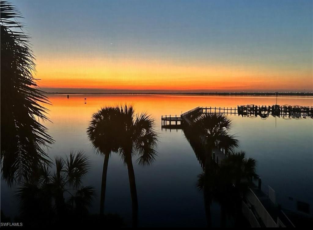 A sunset view over a calm body of water with a wooden pier and palm trees — 5114 MELBOURNE STREET UNIT A302, PUNTA GORDA, FL