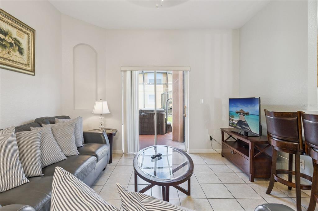 A living room features tile floors, a dark leather sofa, a glass coffee table, and a television — 2717 BUSHMAN DR, KISSIMMEE, FL