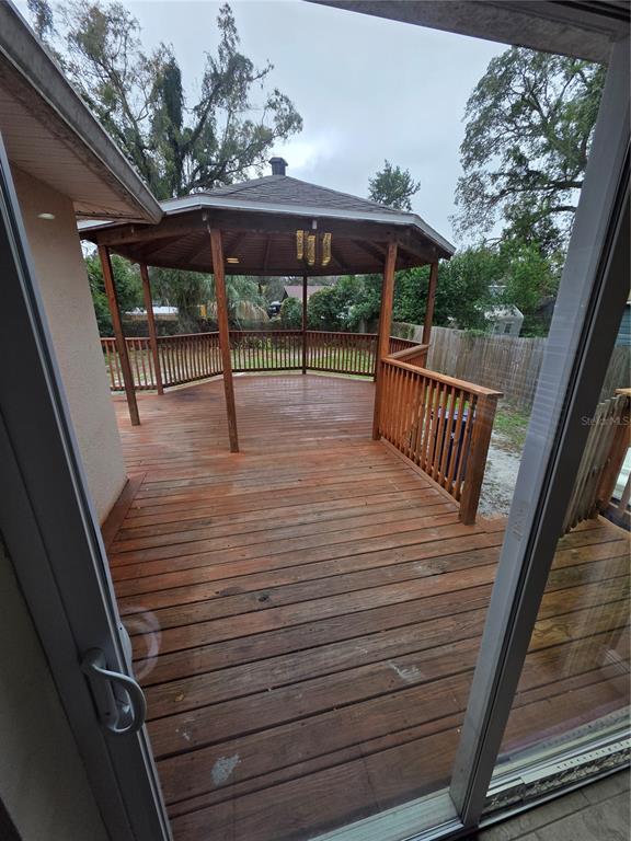 A wooden gazebo sits on a deck with outdoor furniture in a fenced backyard — 1607 E LINEBAUGH AVENUE, TAMPA, FL