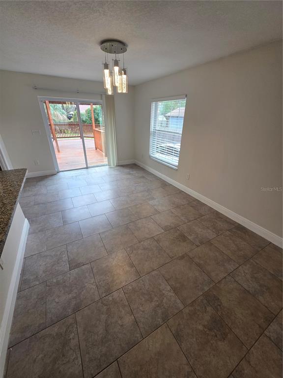 An open-concept kitchen with a breakfast bar overlooks a living area with tile flooring — 1607 E LINEBAUGH AVENUE, TAMPA, FL