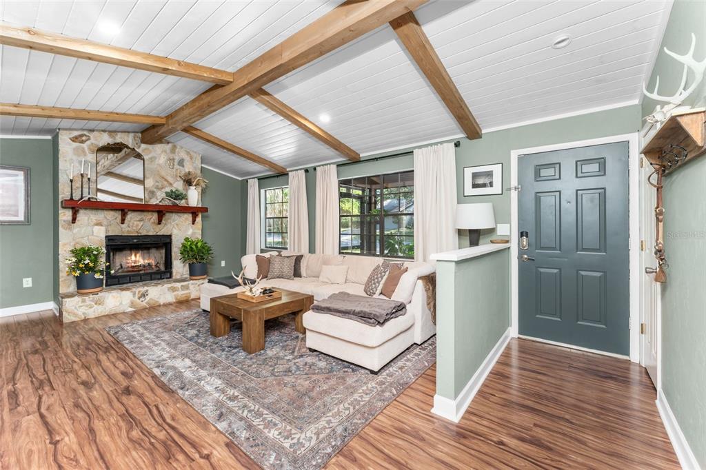 A living room features a stone fireplace, wood-beamed ceiling, and a sectional sofa — 3724 NW 53RD TERRACE, GAINESVILLE, FL