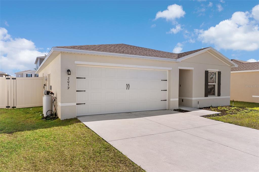 A single-story house with a beige stucco exterior, a two-car garage, and a concrete driveway — 2059 KENTUCKY ROAD, SUMTERVILLE, FL
