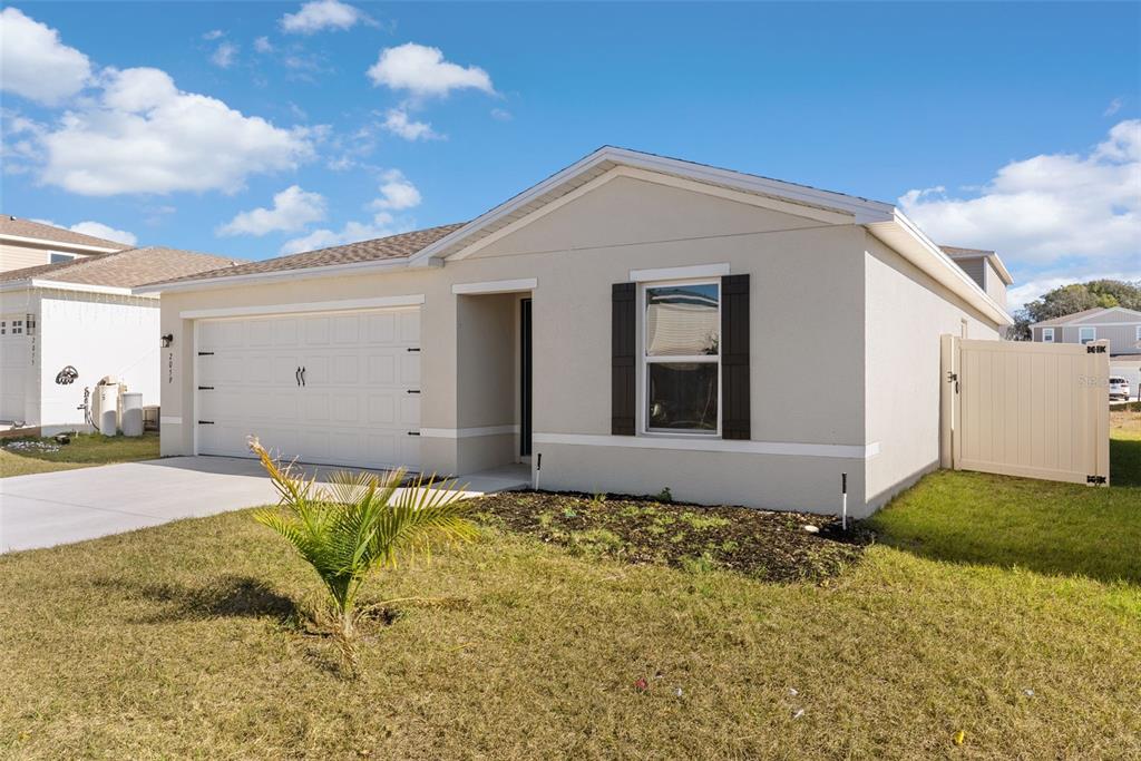 A single-story house with a beige stucco exterior, a two-car garage, and a white fence — 2059 KENTUCKY ROAD, SUMTERVILLE, FL
