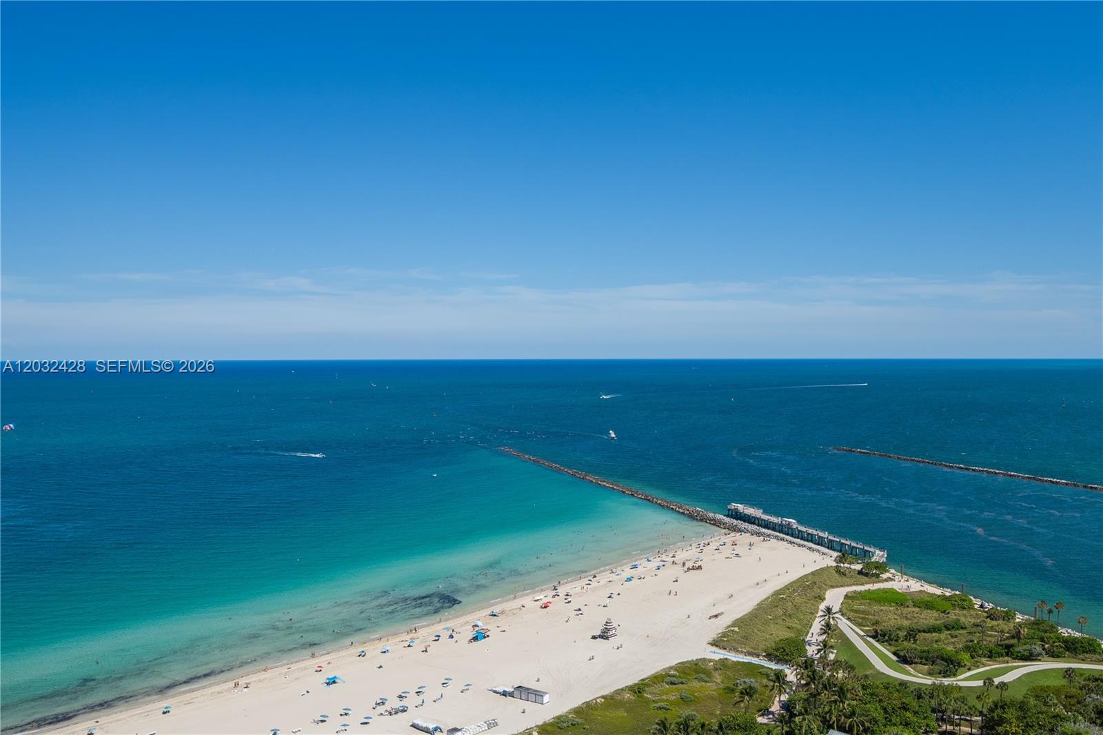 An aerial view shows a sandy beach, a long jetty, and the ocean — 50 S Pointe Dr # 3103, Miami Beach FL 33139, MIAMI BEACH, FL
