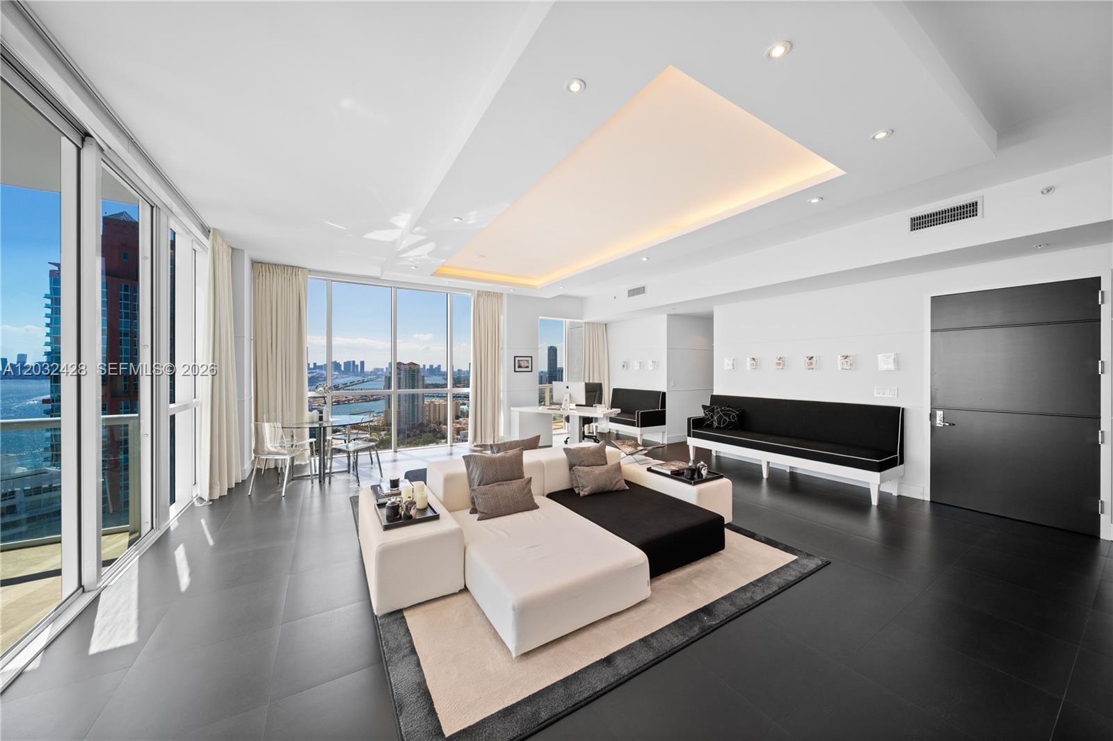 A modern living room features dark tile floors, a white sectional sofa, and floor-to-ceiling windows — 50 S Pointe Dr # 3103, Miami Beach FL 33139, MIAMI BEACH, FL