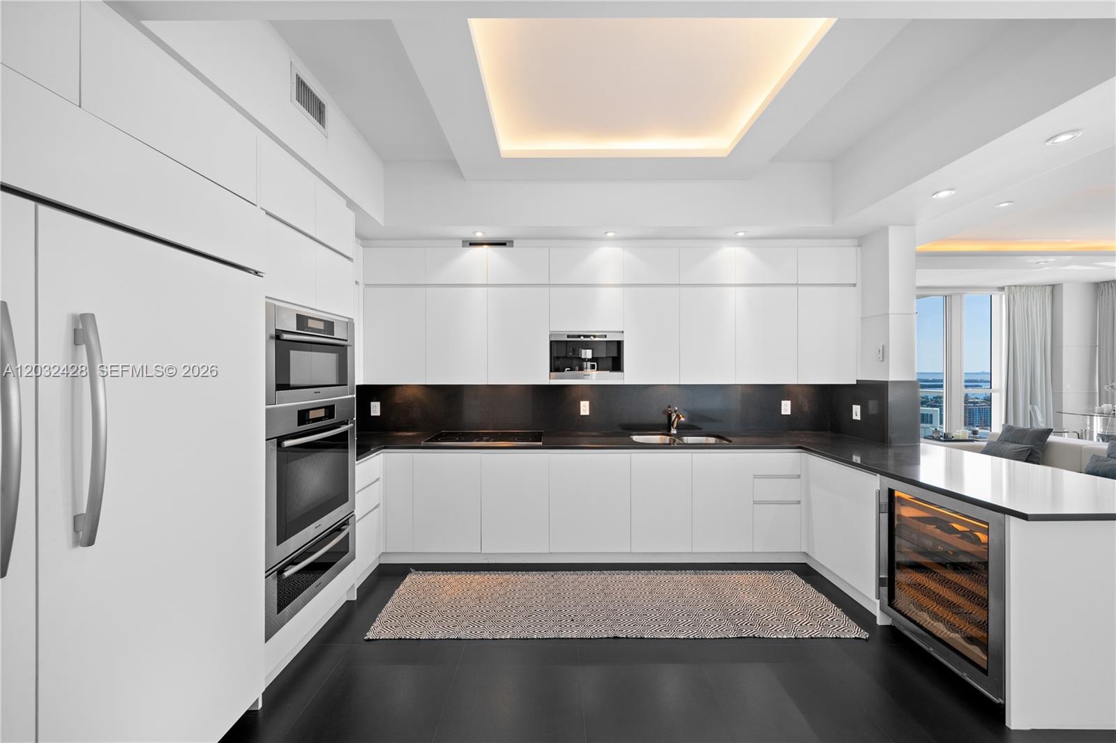 A modern white kitchen features dark countertops, stainless steel appliances, and a wine cooler — 50 S Pointe Dr # 3103, Miami Beach FL 33139, MIAMI BEACH, FL