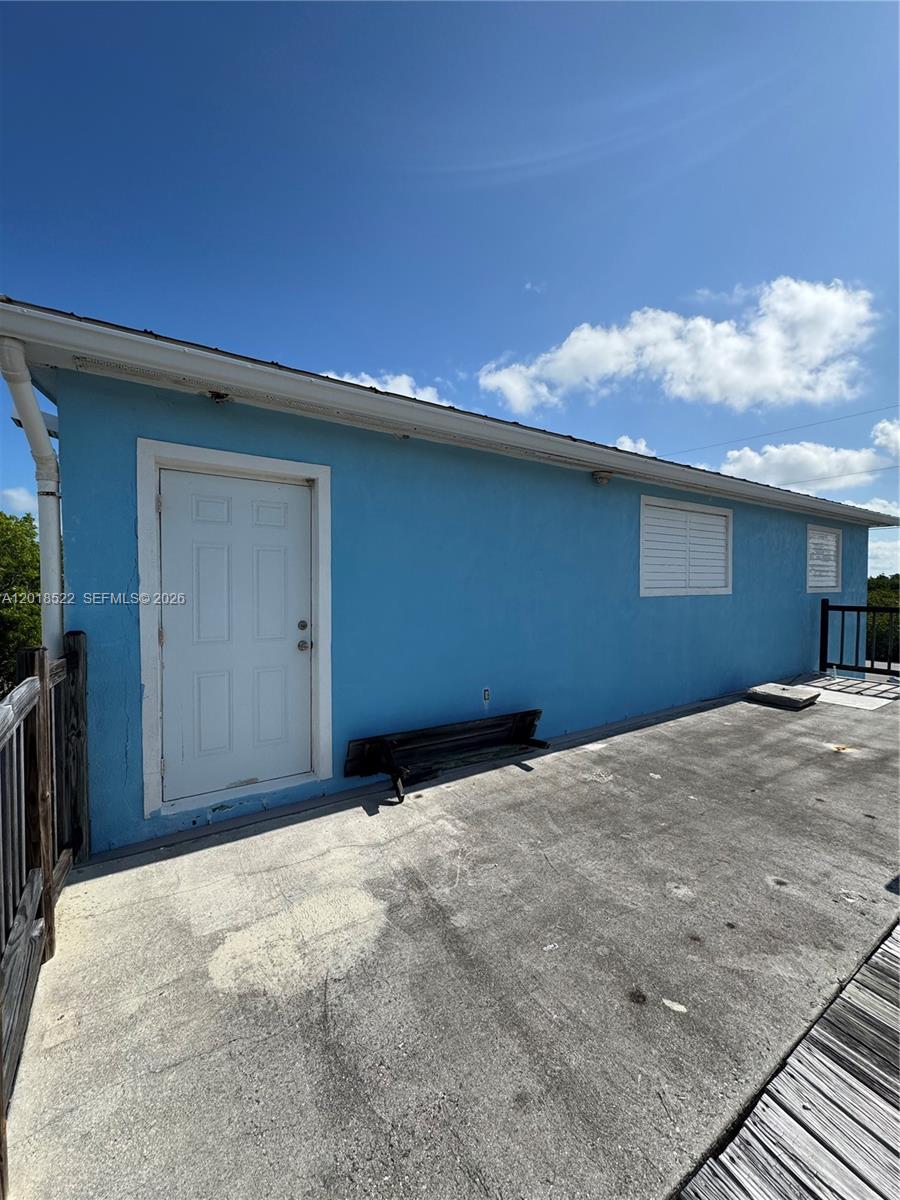 A blue exterior wall features a white door and two windows on a concrete deck — 4276 Dorn Road, Torch Key FL 33042, TORCH KEY, FL