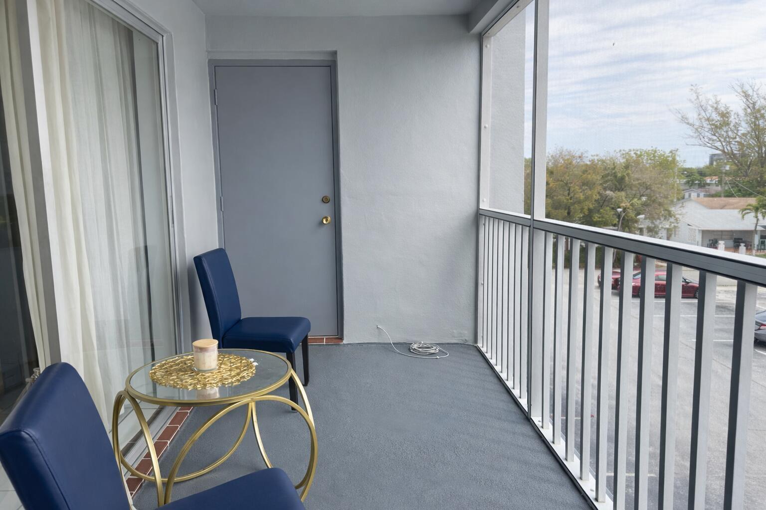 A balcony with two blue chairs, a glass-topped table, and a screened-in railing — 215 SE 3RD Avenue # 306D, Hallandale Beach FL 33009, HALLANDALE BEACH, FL