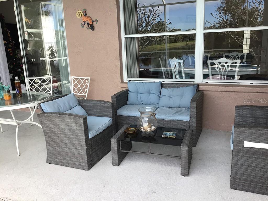 A patio features a wicker furniture set with blue cushions and a glass-topped coffee table — 6222 BUCKINGHAM STREET, SARASOTA, FL