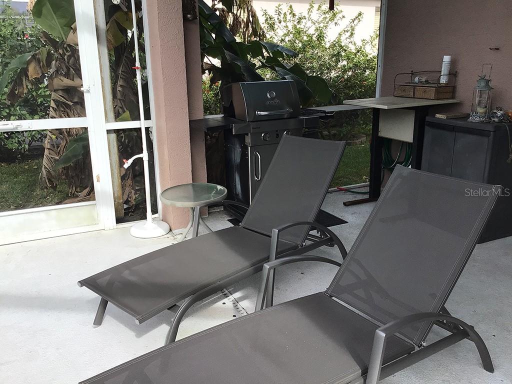 A covered patio features two lounge chairs, a small side table, and a gas grill — 6222 BUCKINGHAM STREET, SARASOTA, FL