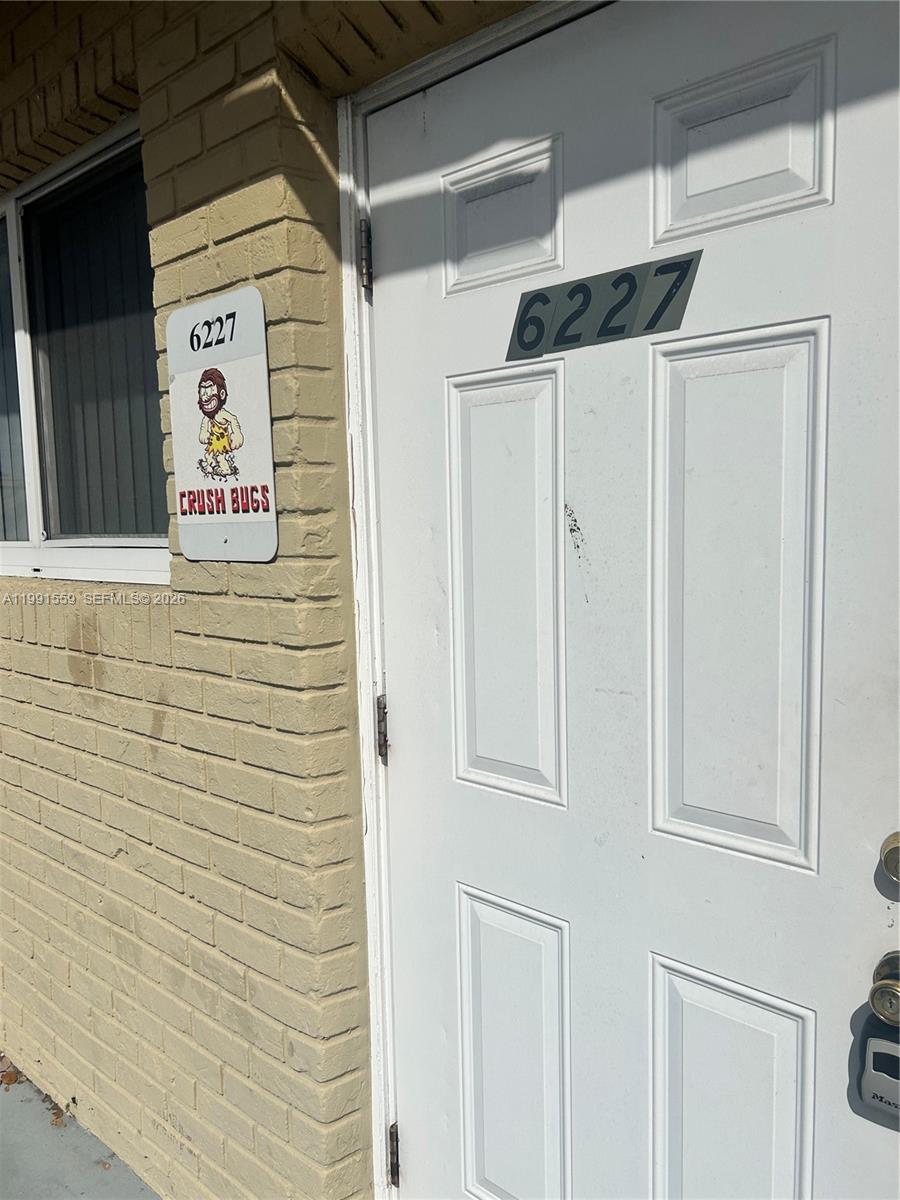 A white door with a house number and a sign featuring a cartoon character — 6225 Johnson St, Hollywood FL 33024, HOLLYWOOD, FL