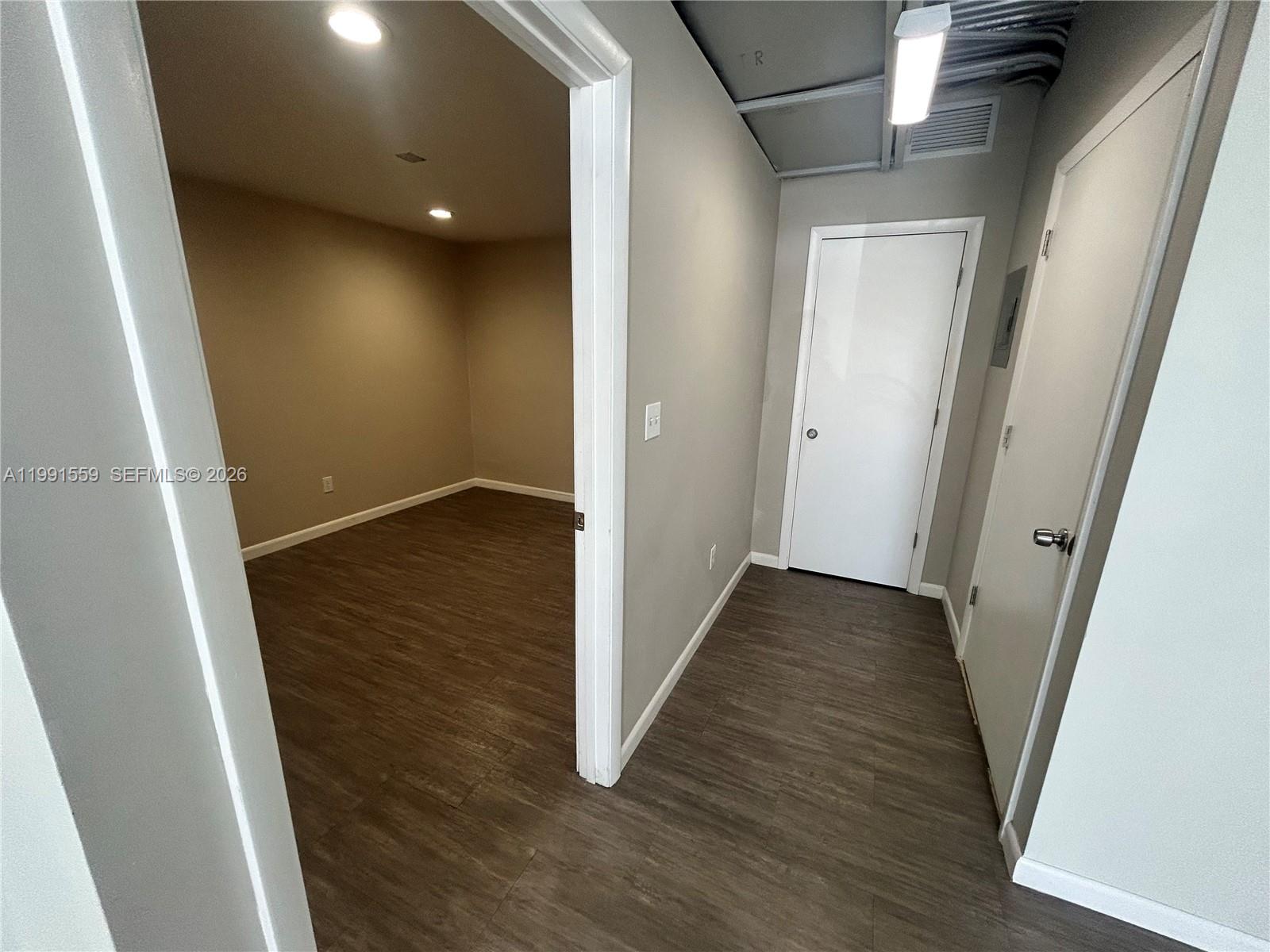 A hallway with wood-look flooring leads to a doorway opening into a beige room — 6225 Johnson St, Hollywood FL 33024, HOLLYWOOD, FL