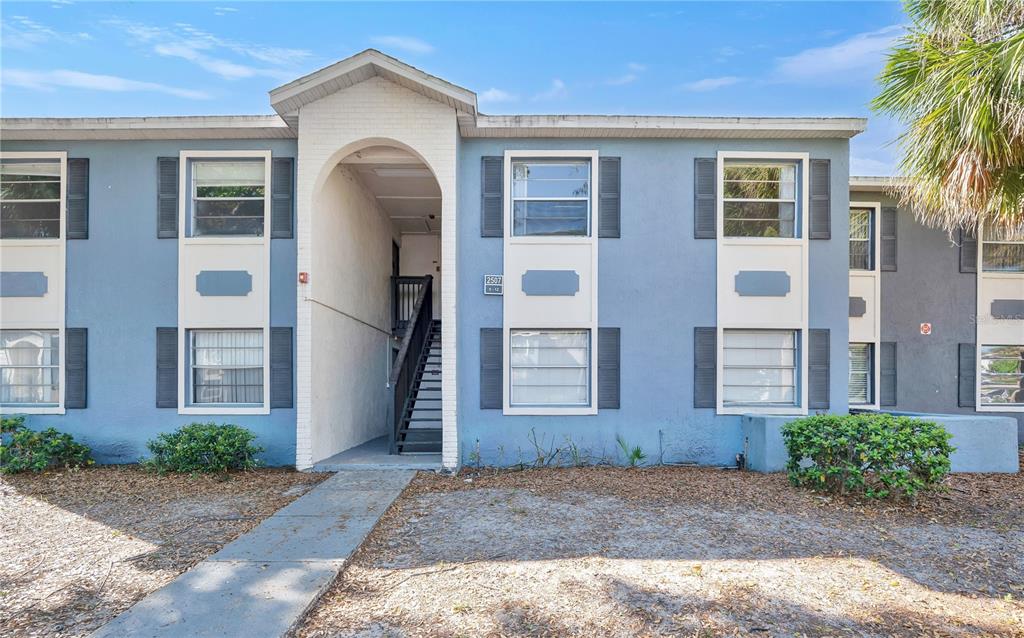 A two-story blue apartment building features an arched entryway with a staircase leading upstairs — 2507 N ALAFAYA TRAIL UNIT 10, ORLANDO, FL