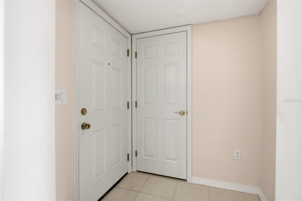 An interior view shows two white doors and a light switch on a beige wall — 2453 EGRET BOULEVARD UNIT O102, CLEARWATER, FL