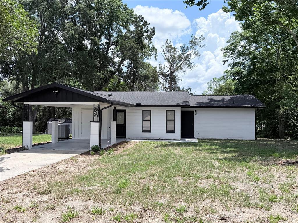 A single-story white house with a black roof and a covered carport — 11 BAHIA COURT LOOP, OCALA, FL