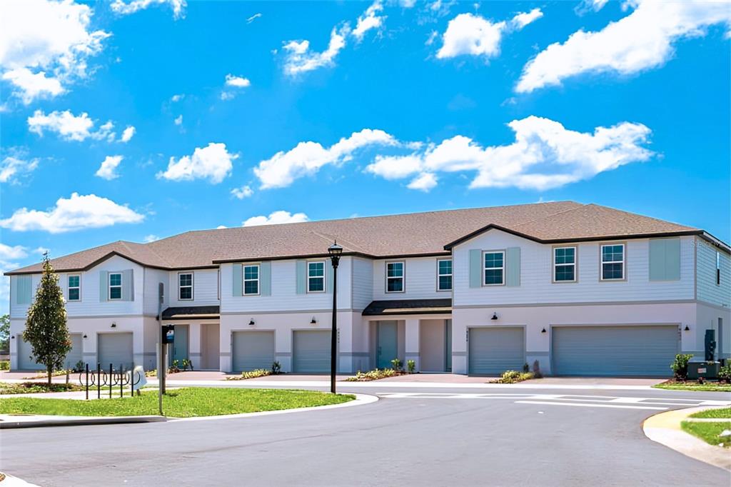 A multi-unit residential building with light-colored siding, multiple garage doors, and a shingled roof — 4899 WINDING RIVER ROAD, ORLANDO, FL