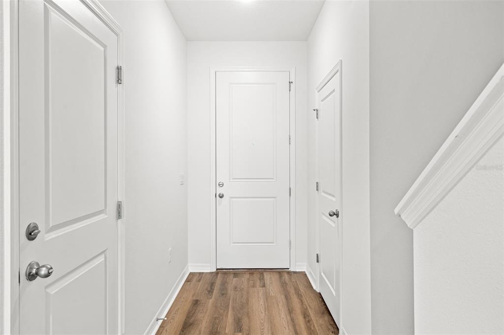 A bright entryway features white walls, a wood-look floor, and three white doors — 4899 WINDING RIVER ROAD, ORLANDO, FL