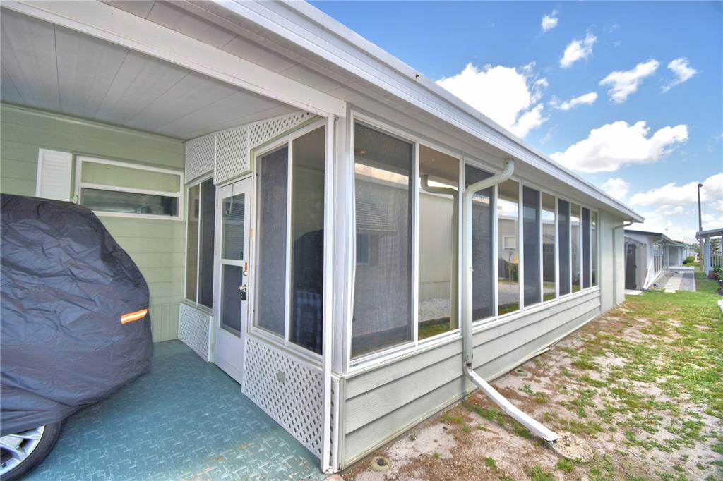 A covered carport area leads to a screened-in porch with light green siding — 4158 ROLLING OAKS DRIVE, WINTER HAVEN, FL