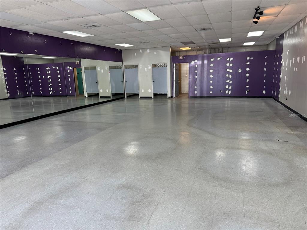 A large, empty studio room features mirrored walls, purple painted accents, and light-colored tile flooring — 14815 N FLORIDA AVENUE UNIT 14815, TAMPA, FL
