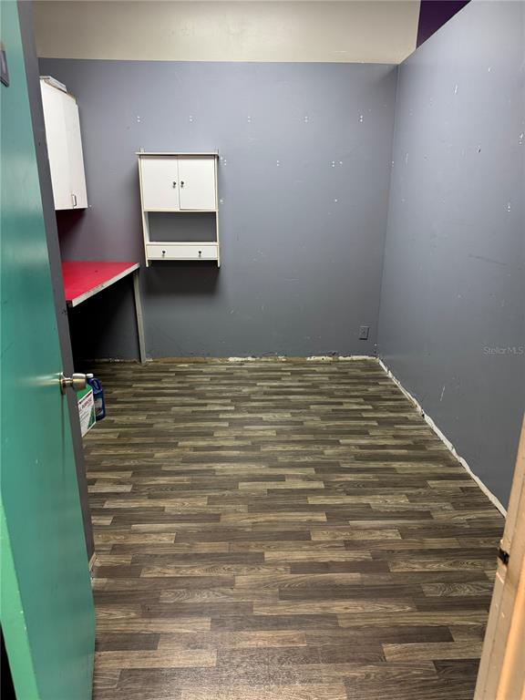 A small room features gray walls, wood-look flooring, a red-topped desk, and wall-mounted cabinets — 14815 N FLORIDA AVENUE UNIT 14815, TAMPA, FL