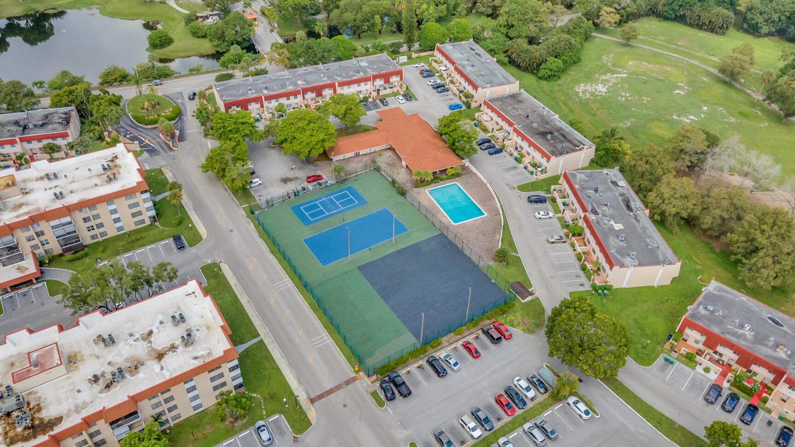 An aerial view shows apartment buildings surrounding a central recreational area with tennis courts and pool — 4166 Inverrary Drive # 304, Lauderhill FL 33319, LAUDERHILL, FL