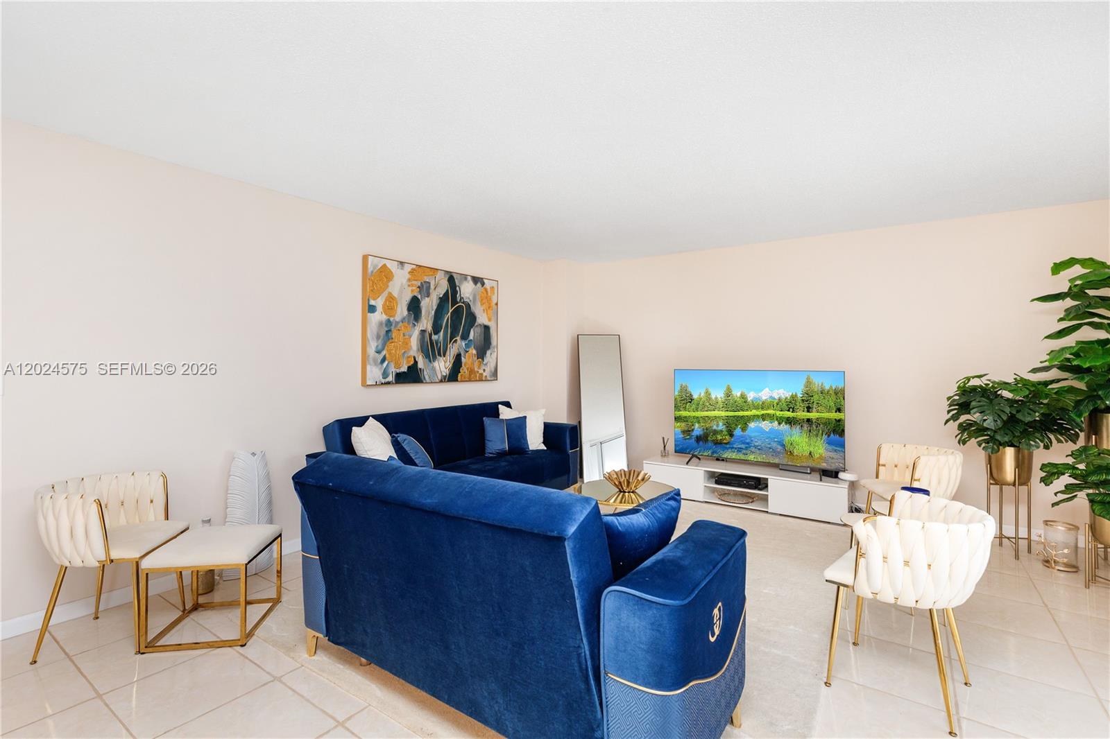 A living room features two blue velvet sofas, white chairs, and a television on a stand — 2030 S Ocean Dr # 307, Hallandale Beach FL 33009, HALLANDALE BEACH, FL