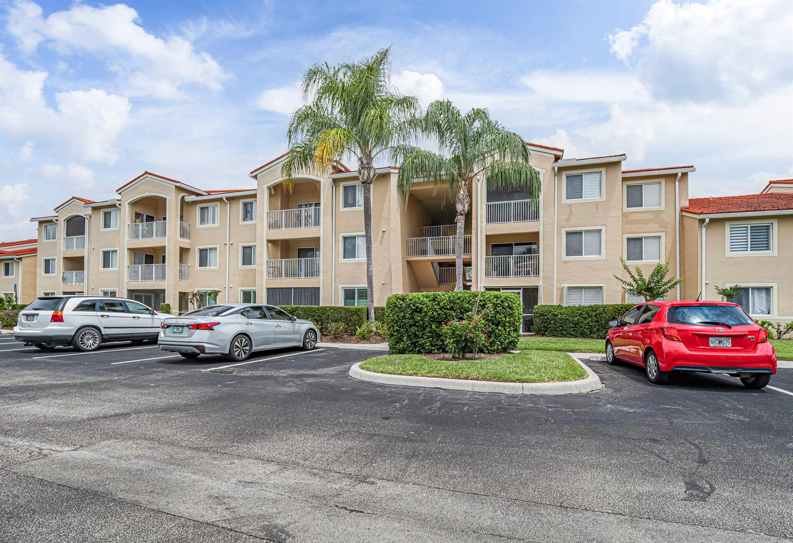 A multi-story apartment building with tan stucco walls and a red tile roof — VERO BEACH, FL