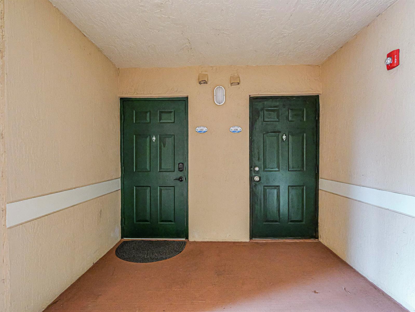 Two dark green entry doors are positioned side-by-side on a tan stucco exterior wall — VERO BEACH, FL