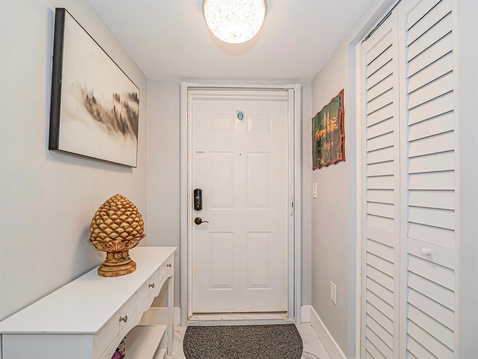 An entryway features a white console table, a pinecone sculpture, a front door, and shutters — VERO BEACH, FL