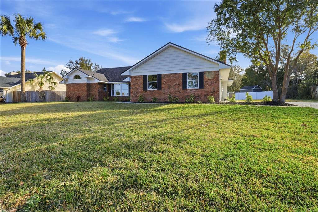 A single-story brick house with a white gable and a large front lawn — 33608 OVERTON DRIVE, LEESBURG, FL
