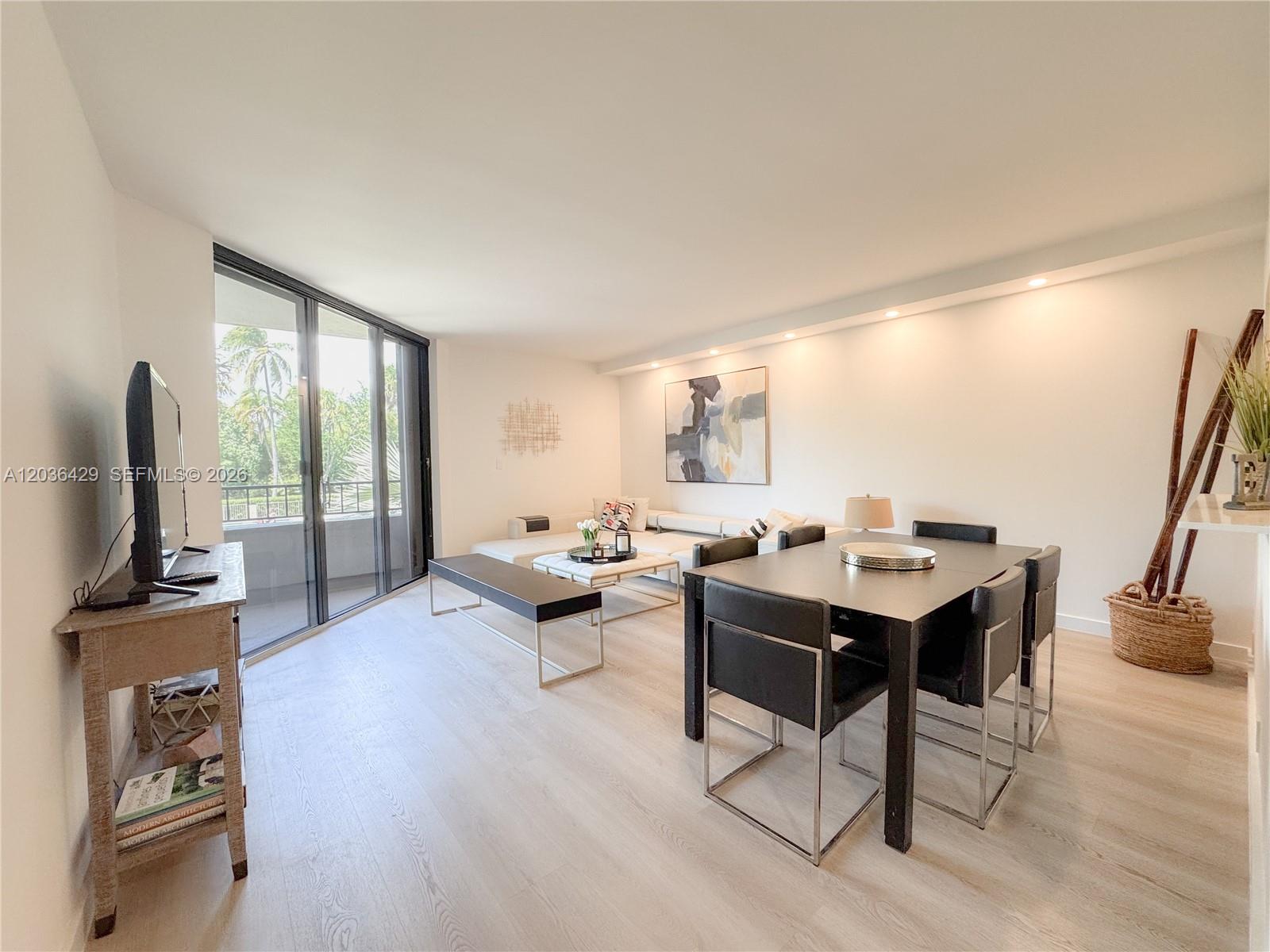A bright living and dining area features light wood floors, modern furniture, and a balcony — 101 Crandon Blvd # 170, Key Biscayne FL 33149, KEY BISCAYNE, FL