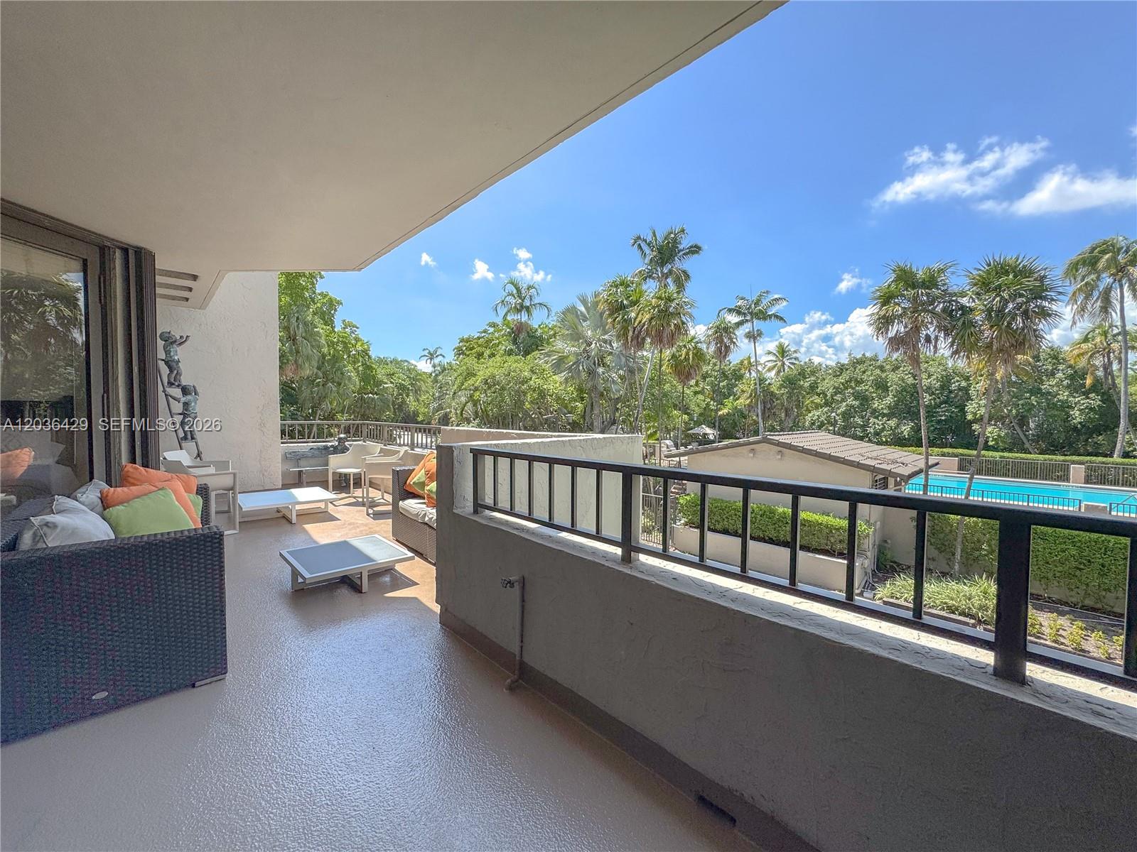 A balcony with outdoor furniture overlooks a swimming pool and lush tropical landscaping — 101 Crandon Blvd # 170, Key Biscayne FL 33149, KEY BISCAYNE, FL