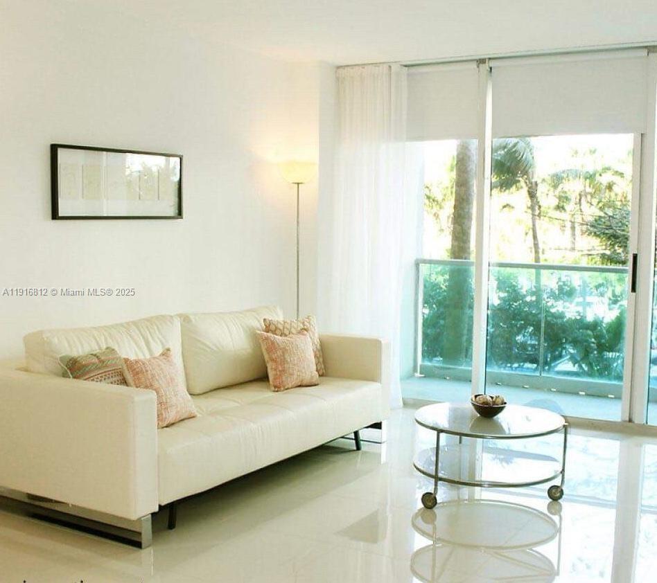 A living room features a white sofa, a glass coffee table, and a balcony view — 4001 S Ocean Dr # 2H, Hollywood FL 33019, HOLLYWOOD, FL