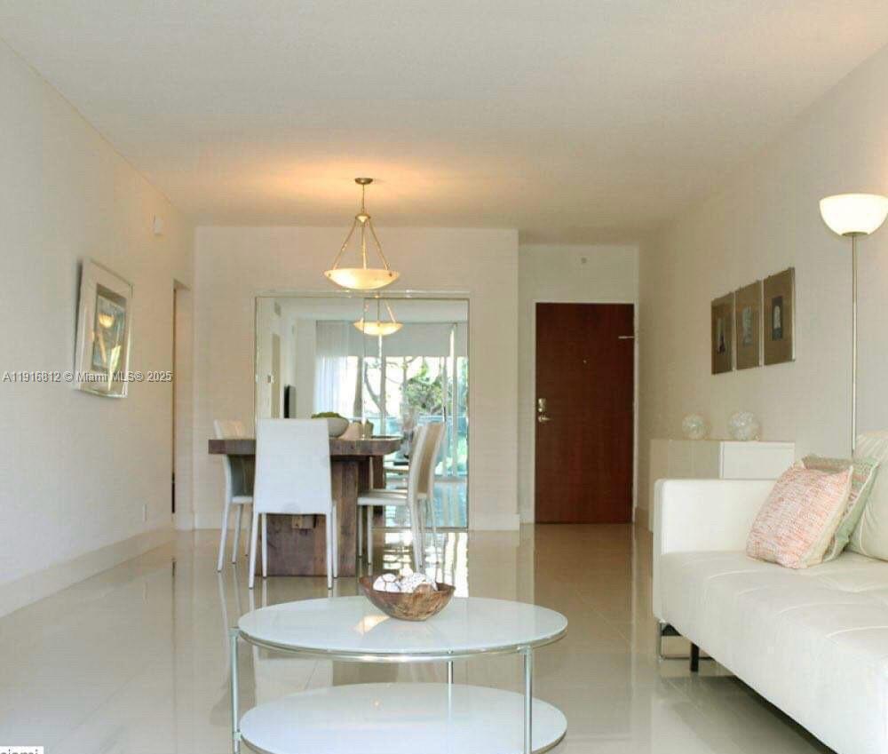 A bright living and dining area features white tile floors, a white sofa, and mirrors — 4001 S Ocean Dr # 2H, Hollywood FL 33019, HOLLYWOOD, FL