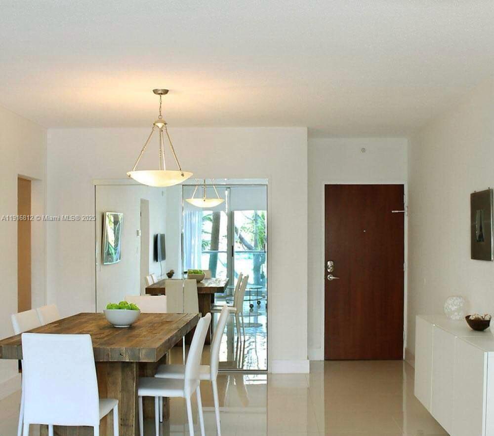 A dining room features a wooden table, white chairs, a pendant light, and mirrored walls — 4001 S Ocean Dr # 2H, Hollywood FL 33019, HOLLYWOOD, FL