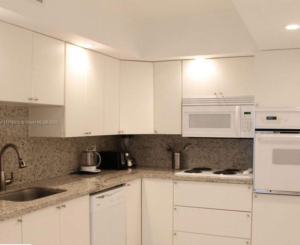 A kitchen with white cabinets, granite countertops, and white appliances — 4001 S Ocean Dr # 2H, Hollywood FL 33019, HOLLYWOOD, FL