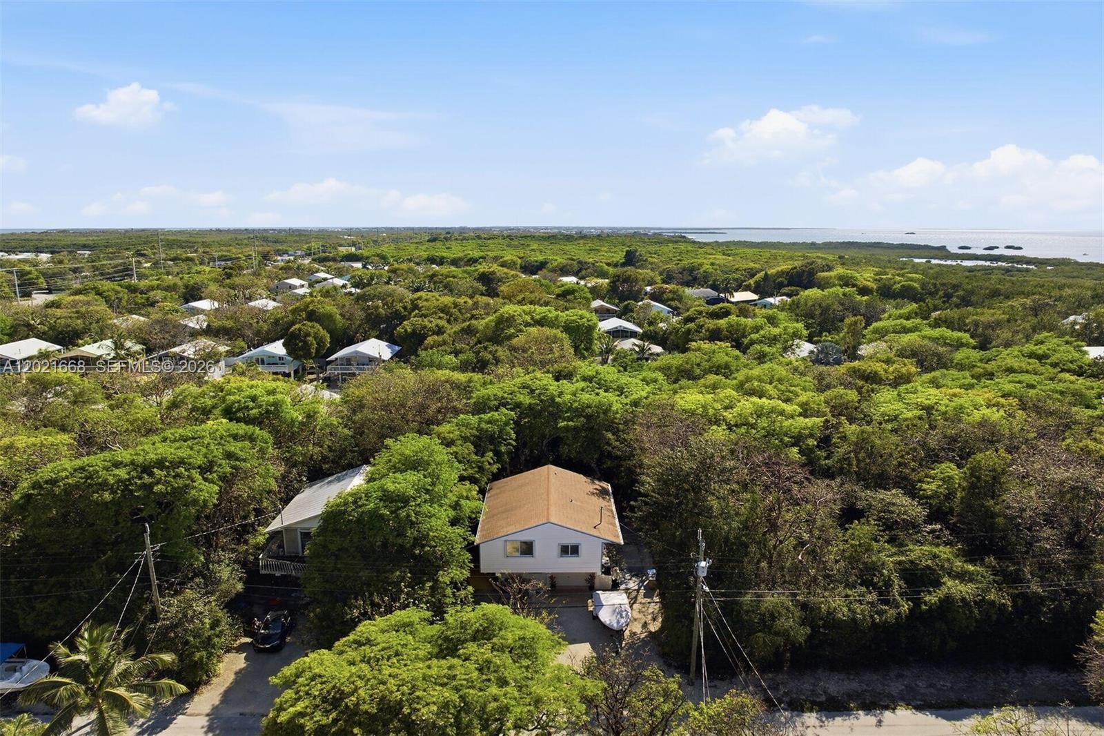 An aerial view shows a house surrounded by dense trees near a coastal body of water — 323 Bay View Ave, Key Largo FL 33037, KEY LARGO, FL