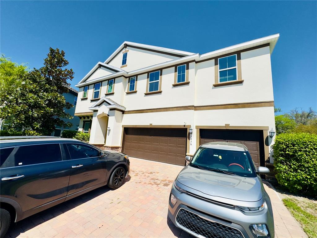 A two-story house with a three-car garage and two parked cars in the driveway — 3436 STONEWYCK STREET, ORLANDO, FL