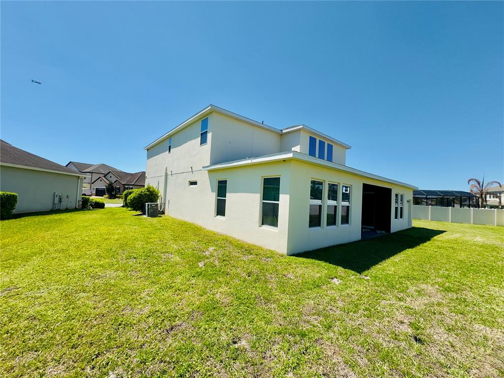 The exterior of a two-story house with a light-colored stucco finish and a grassy yard — 3436 STONEWYCK STREET, ORLANDO, FL
