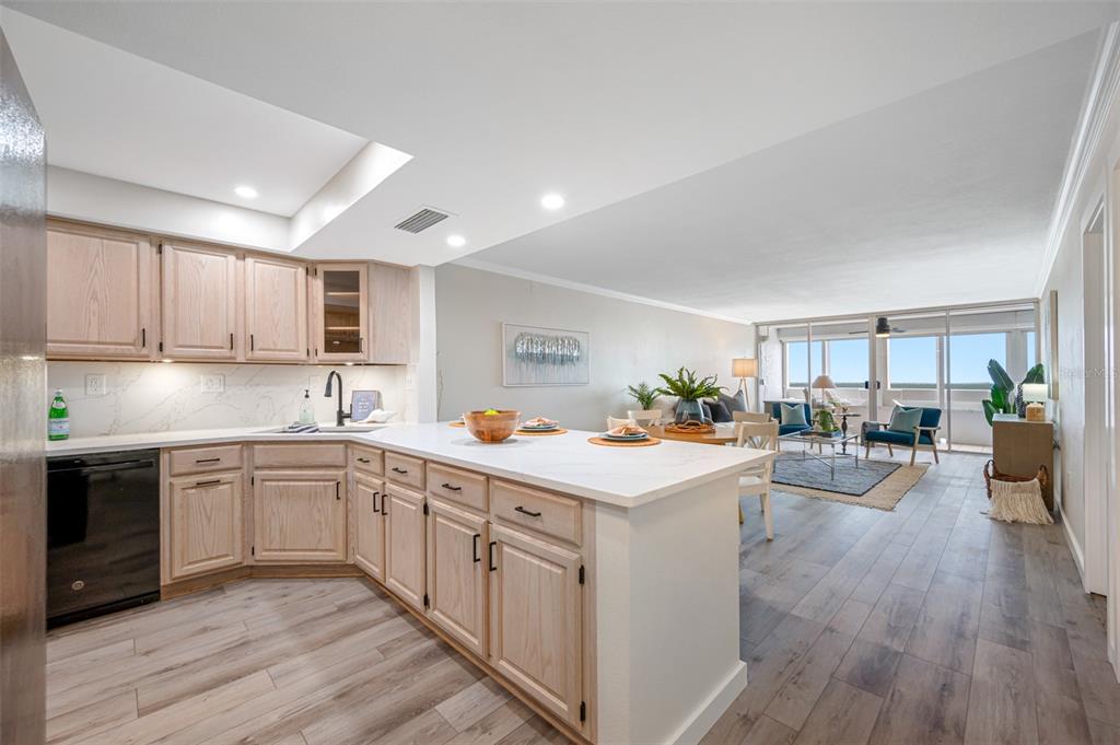 A kitchen with light wood cabinets and white countertops overlooks an open-concept living area — 17920 GULF BOULEVARD UNIT 2008, REDINGTON SHORES, FL
